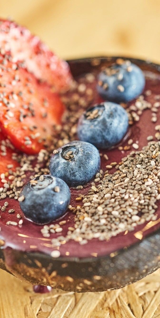 Açaí bowl in a coconut shell with strawberries and blueberries